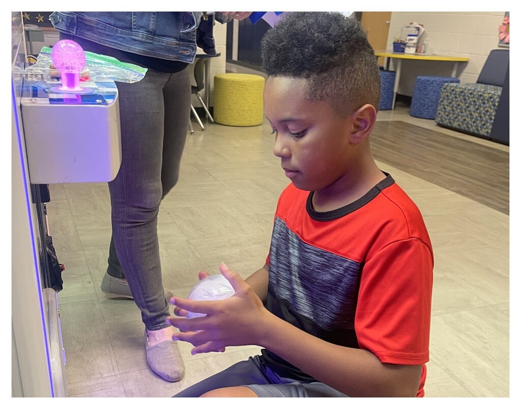 Student looking at a prize that came out of a claw machine
