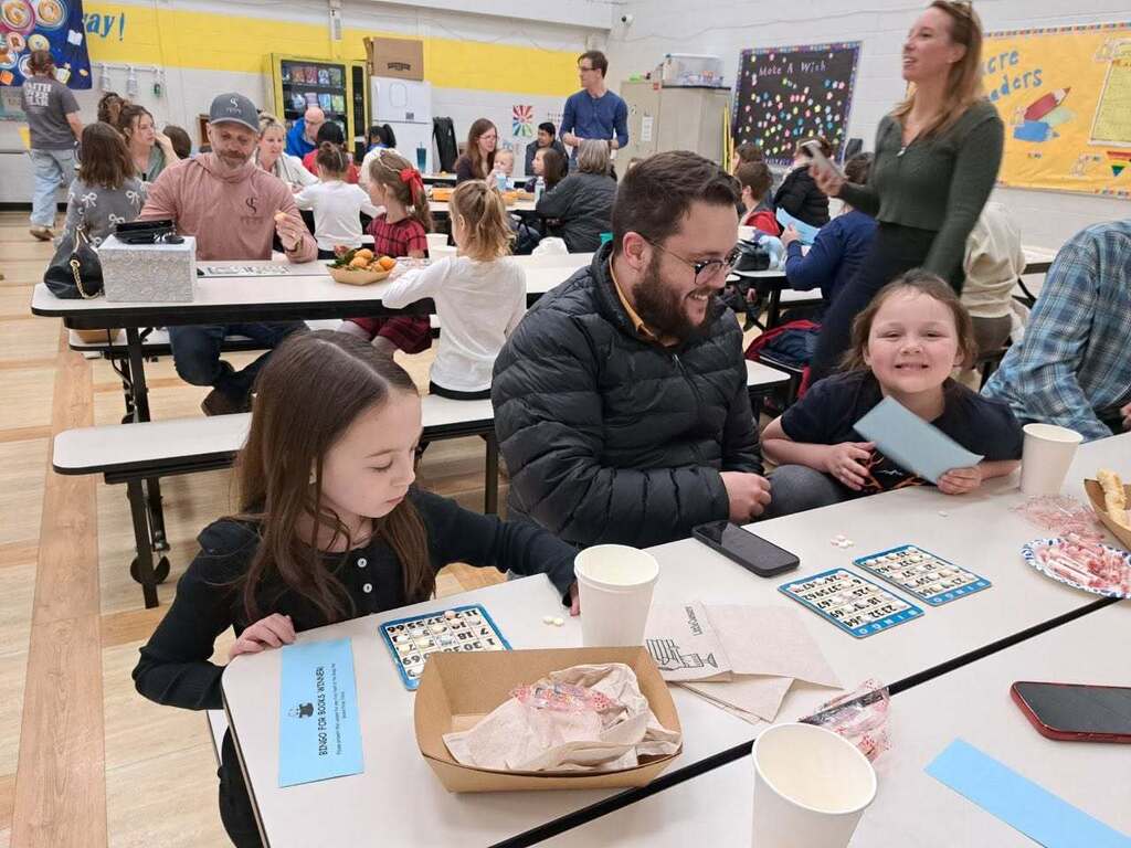 Two students and their dad sitting at a table playing bingo.