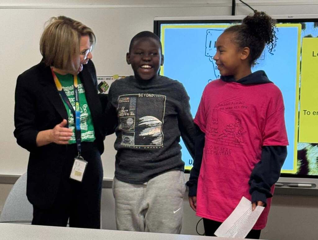 Two students standing with a teacher, laughing