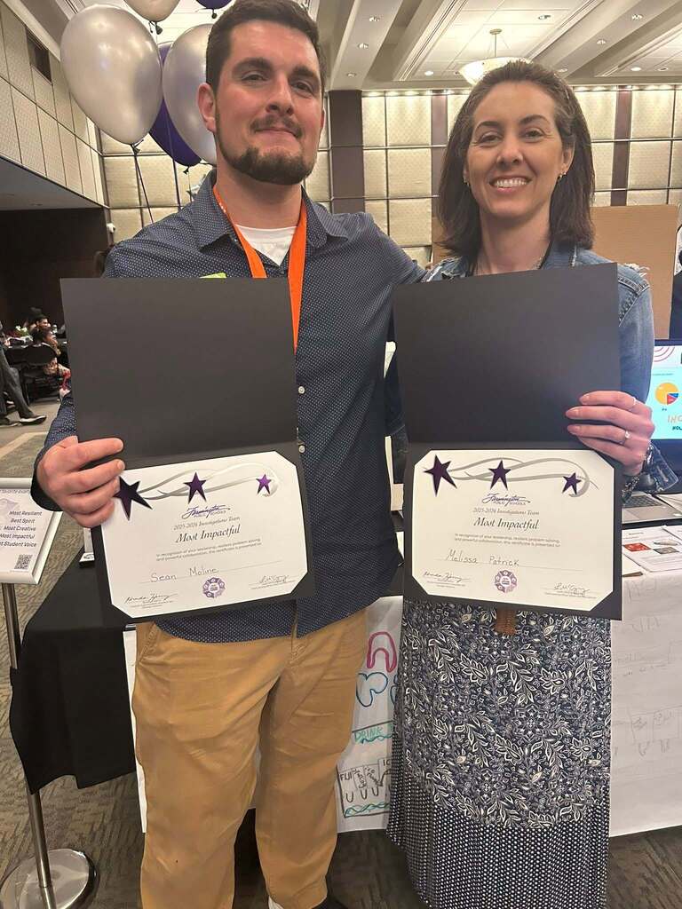 Two educators showing off awards.