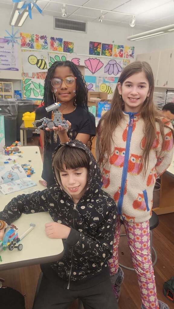 Three students showing off their completed projects