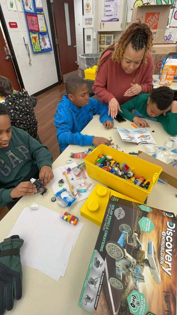 Students working together to create robots with help of an adult aid