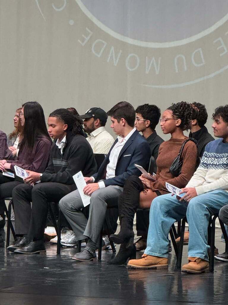 Close up photo of about 12 IB graduates sitting together on stage.