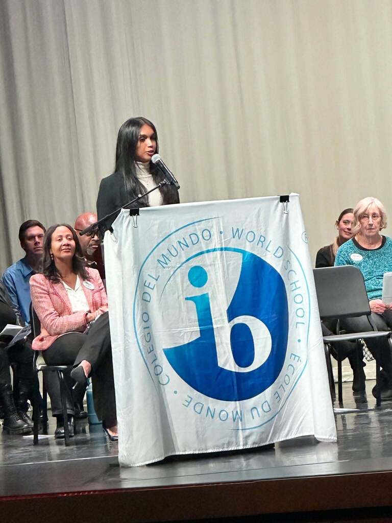 IB former graduate standing at the podium speaking to the graduates.