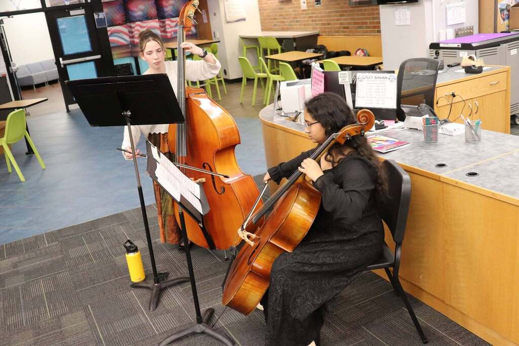 Two students playing the cello.