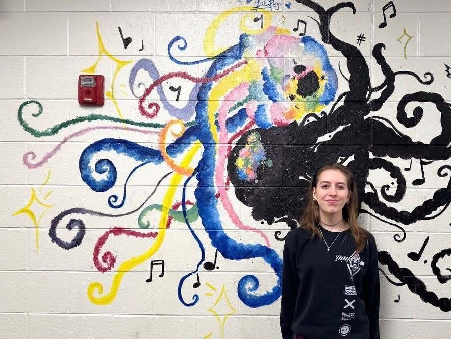 FHS student standing in front of her mural done for NAHS.