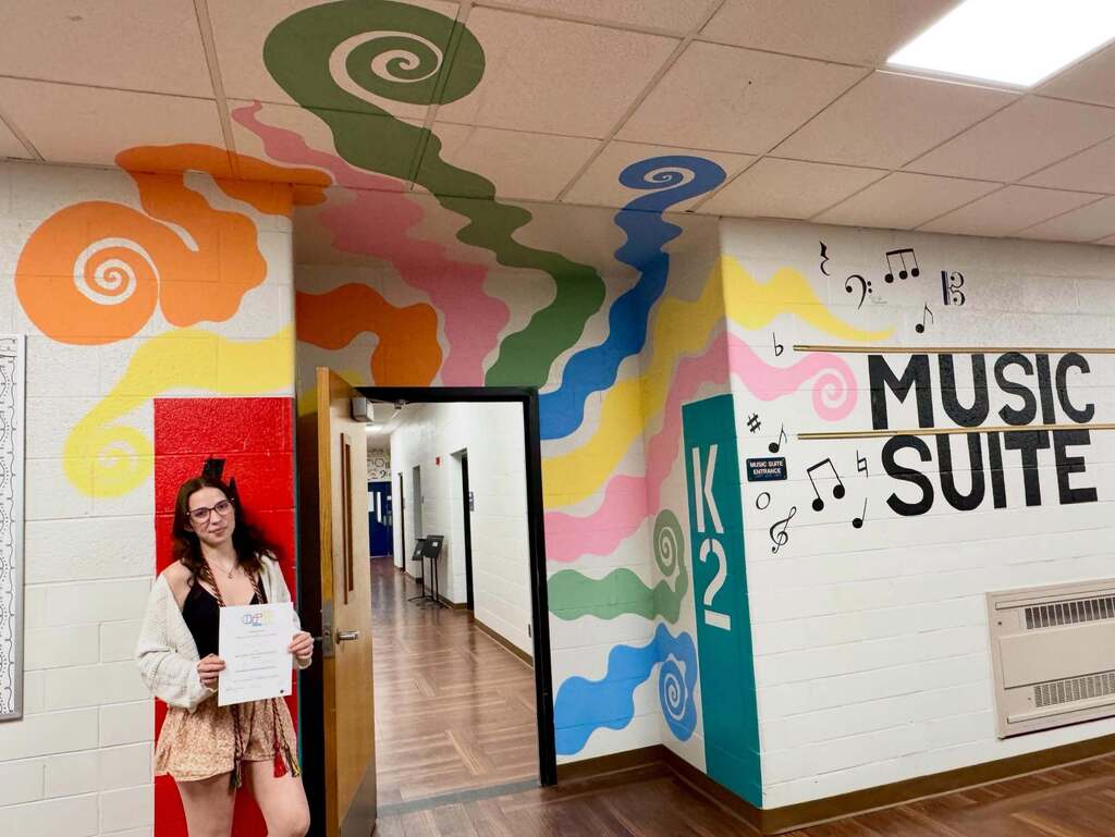FHS student standing in front of her mural done for NAHS.