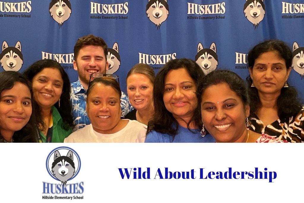 Group of smiling adults posing in front of a Hillside Elementary School Huskies backdrop at a leadership event.