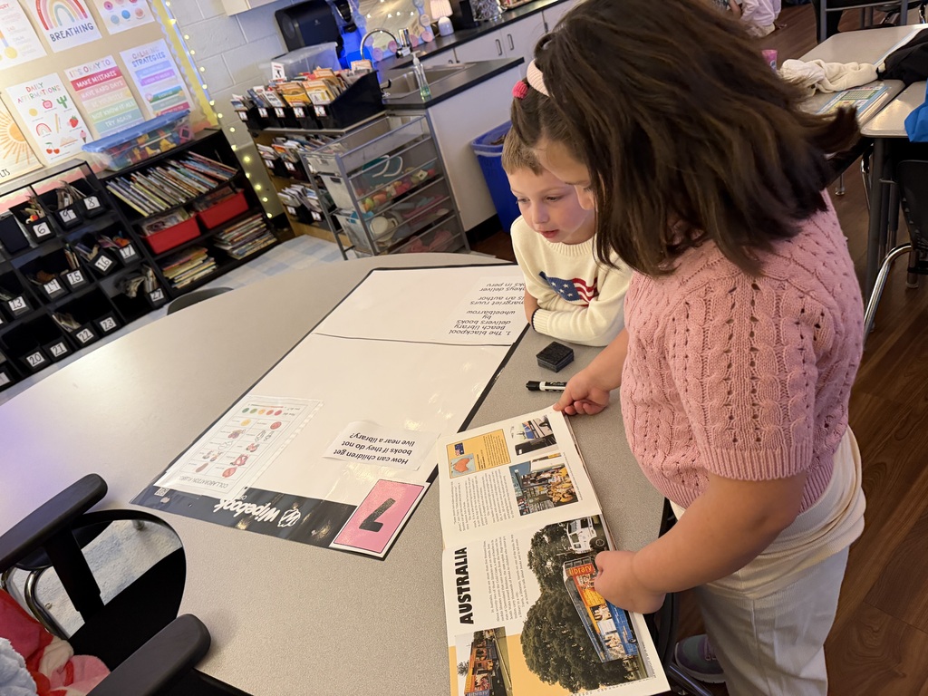 a young girl and boy looking at a book about Australia
