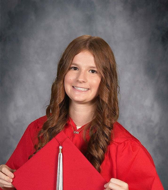 student posing in graduation gown holding graduation cap
