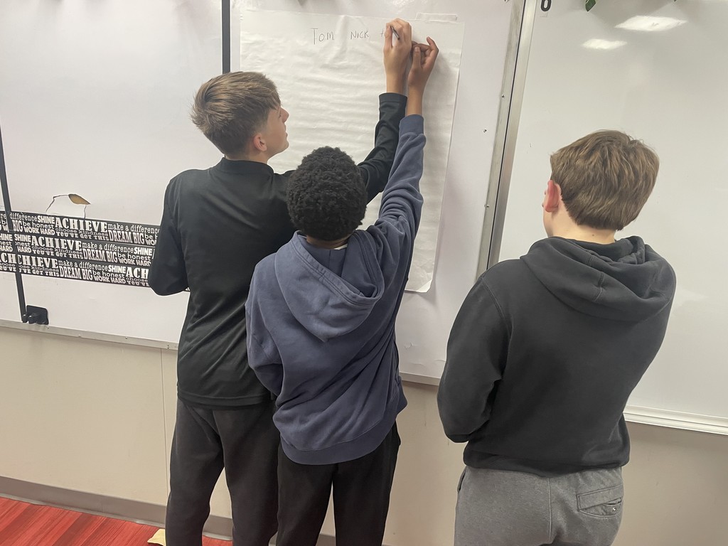 Students in writing on a paper taped to the whiteboard