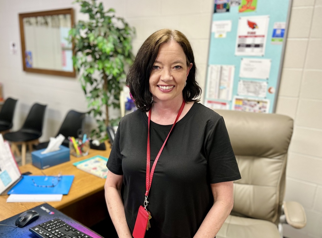 Paula Beard standing at her desk, smiiling for camera