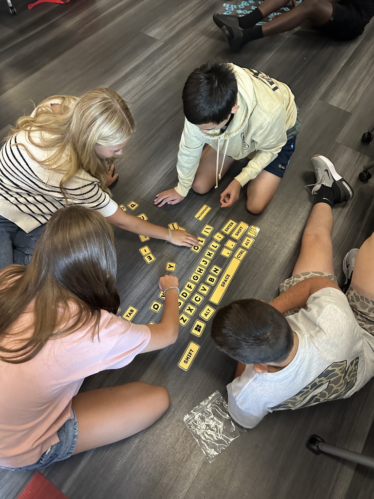 Students sitting on the floor, arranging keyboard keys