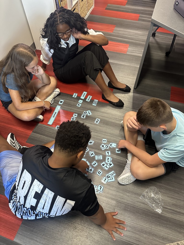 Students sitting on the floor, arranging keyboard keys