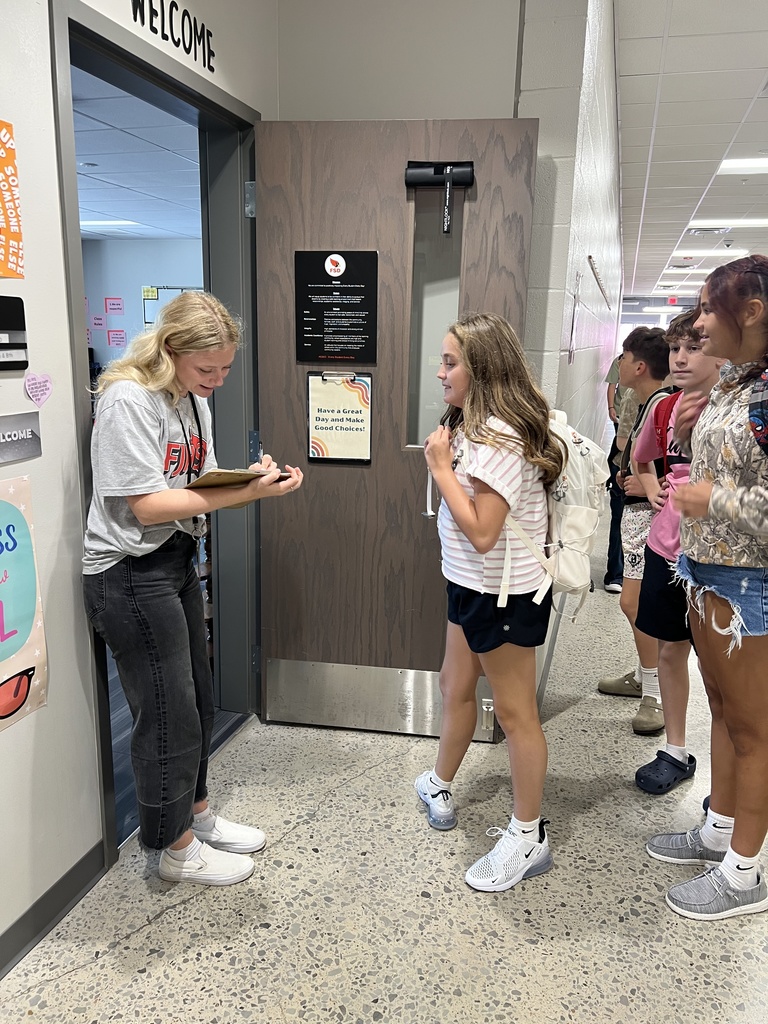 Teacher greets a student at the door