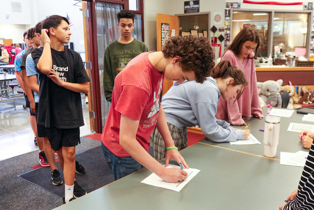 Students standing in line, student signs paper