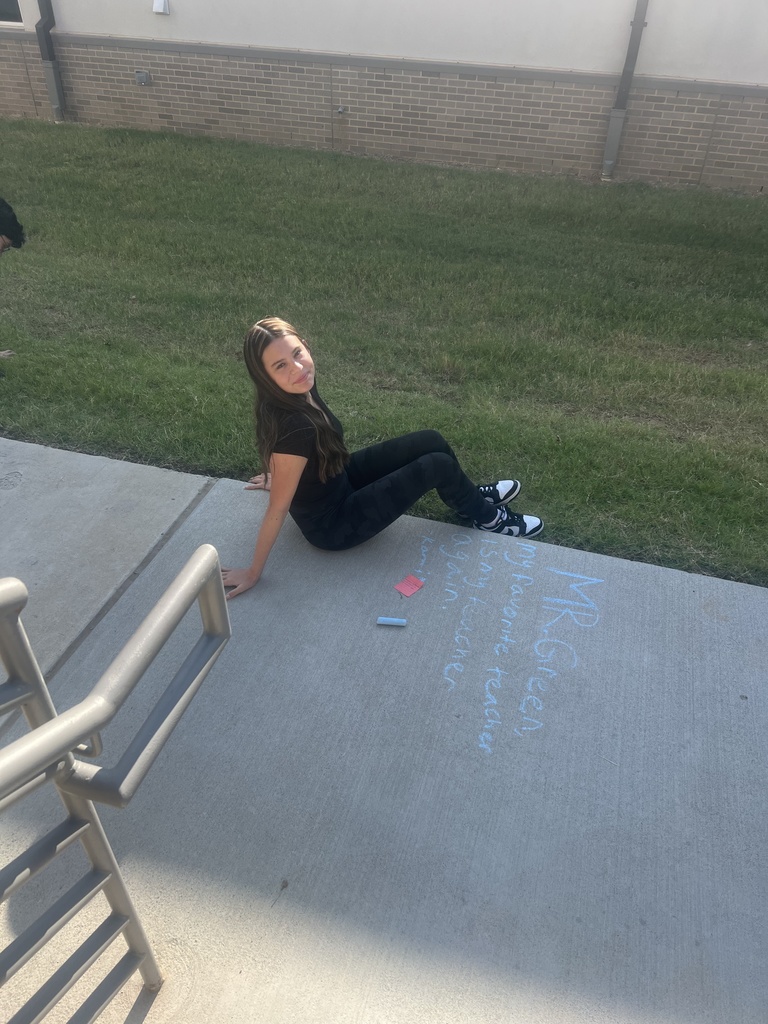 Student smiling after writing on sidewalk in chalk