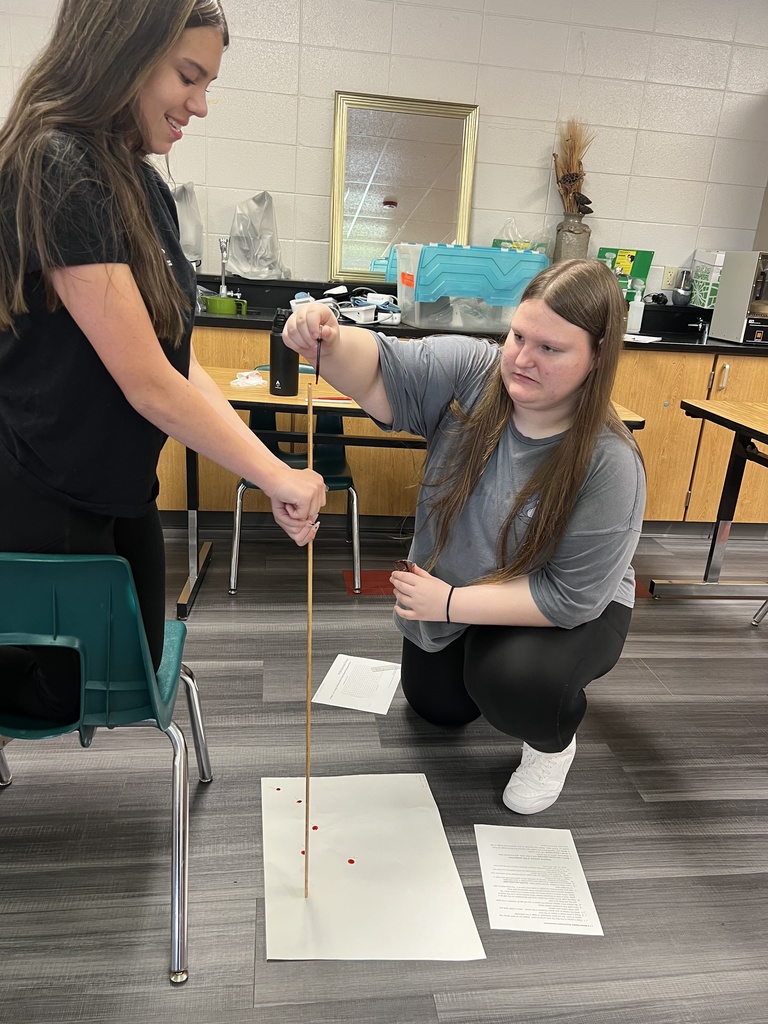 Student on the floor, measuring drops with a yard stick