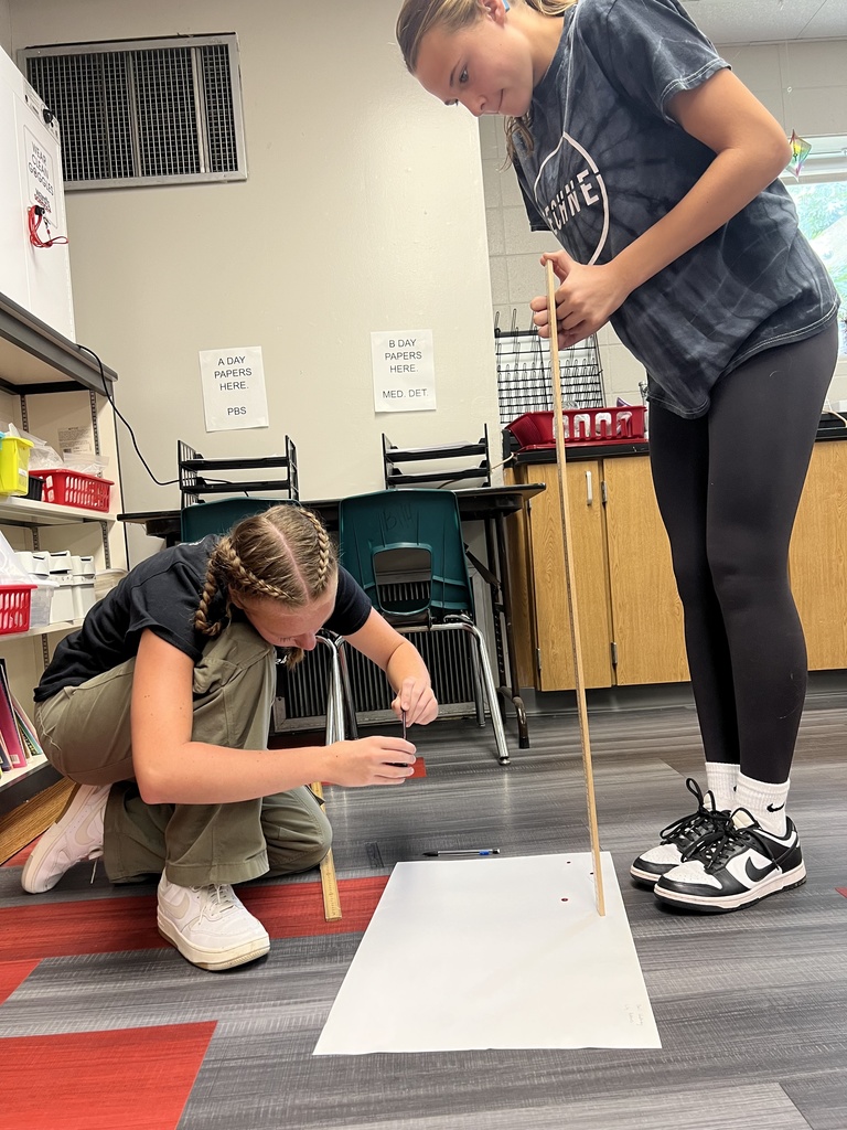 Student on the floor, measuring drops with a yard stick