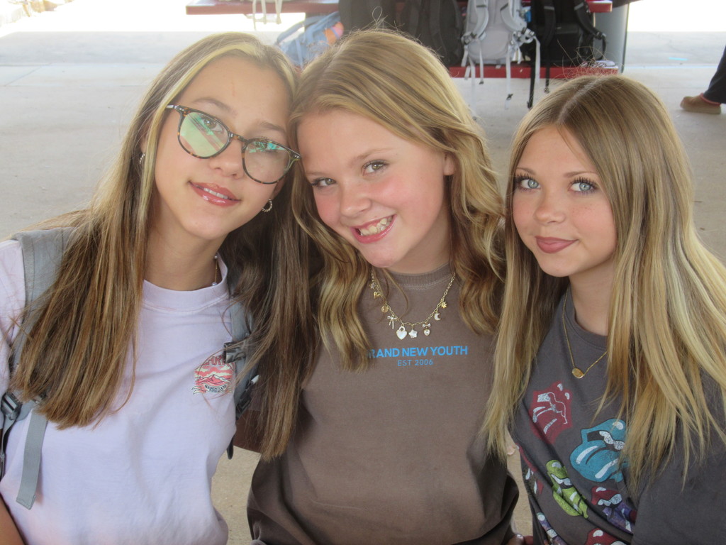 Three girls sitting outside together.