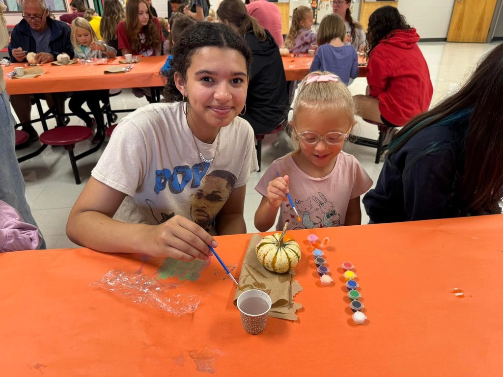 FJHS Student helping pre-k student paint pumpkin