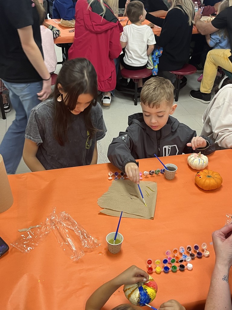 FJHS Student helping pre-k student paint pumpkin