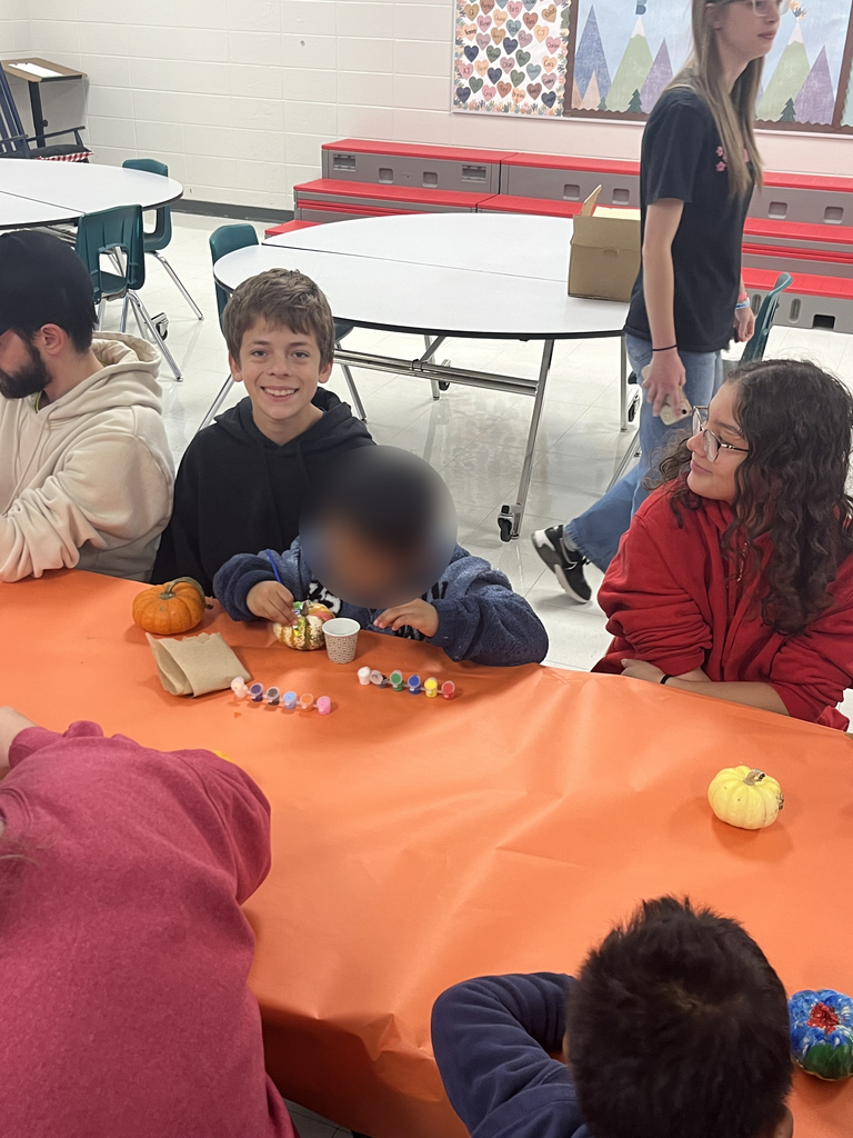 FJHS Student helping pre-k student paint pumpkin