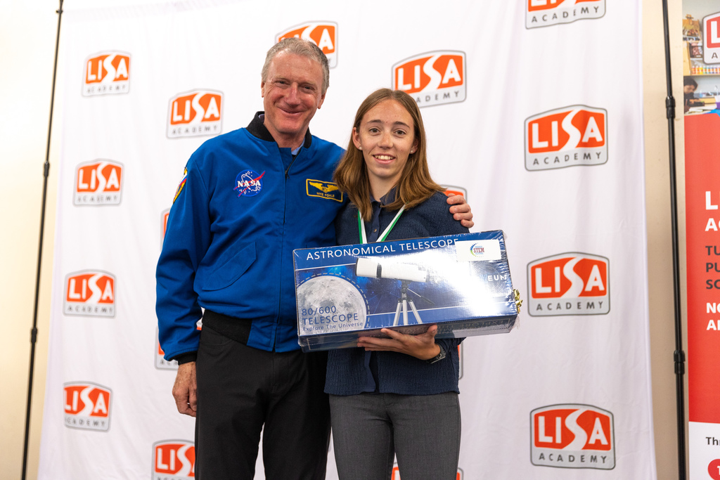 student posing with astronaut on stage