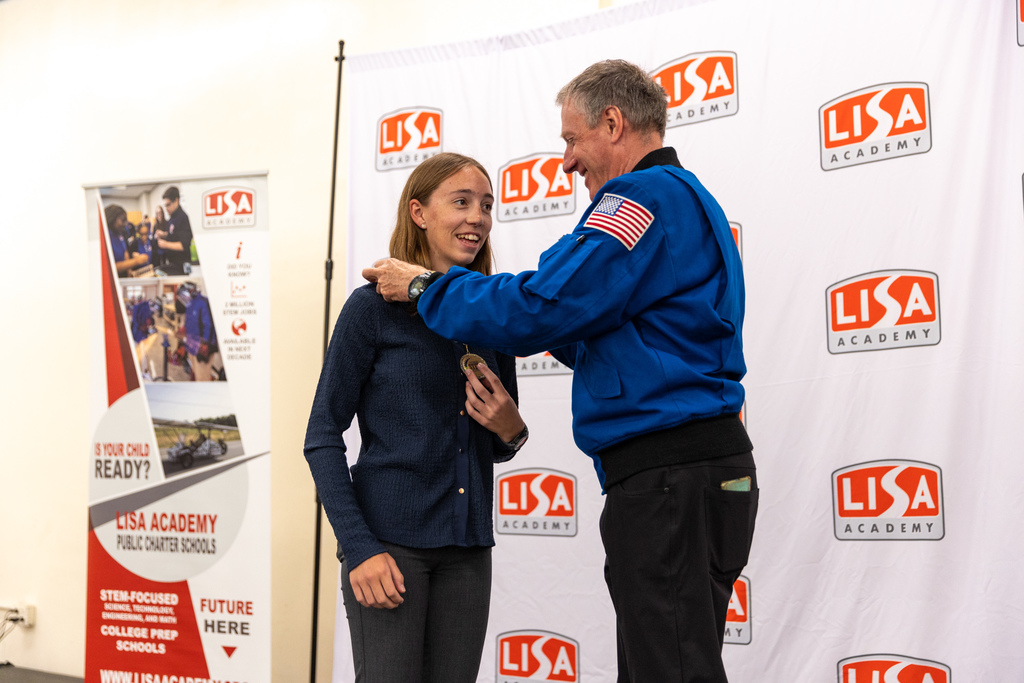 student receiving medal from astronaut on stage