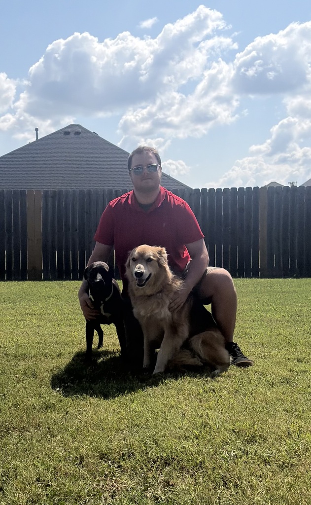 teacher posing in a yard with two dogs