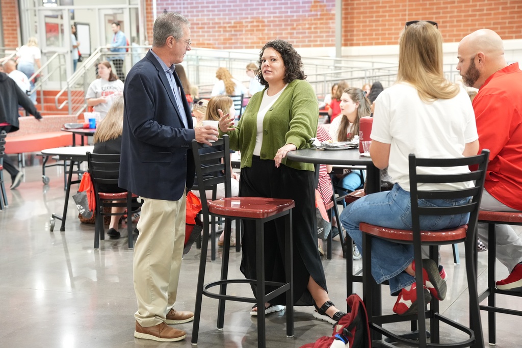 A group of people sitting and standing at tables in a dining area with brick walls.