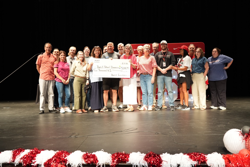 People on stage holding a large check, with pom-poms in the foreground.