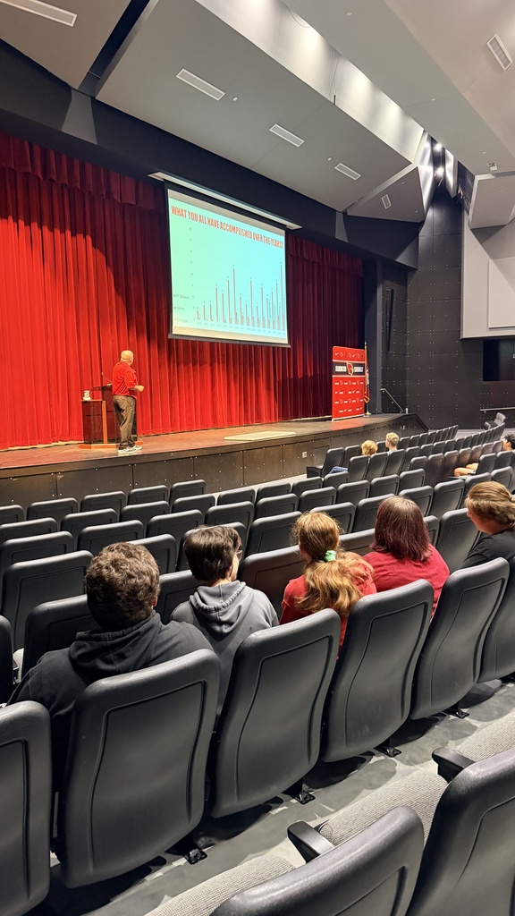 administrator presenting to students in performing arts center
