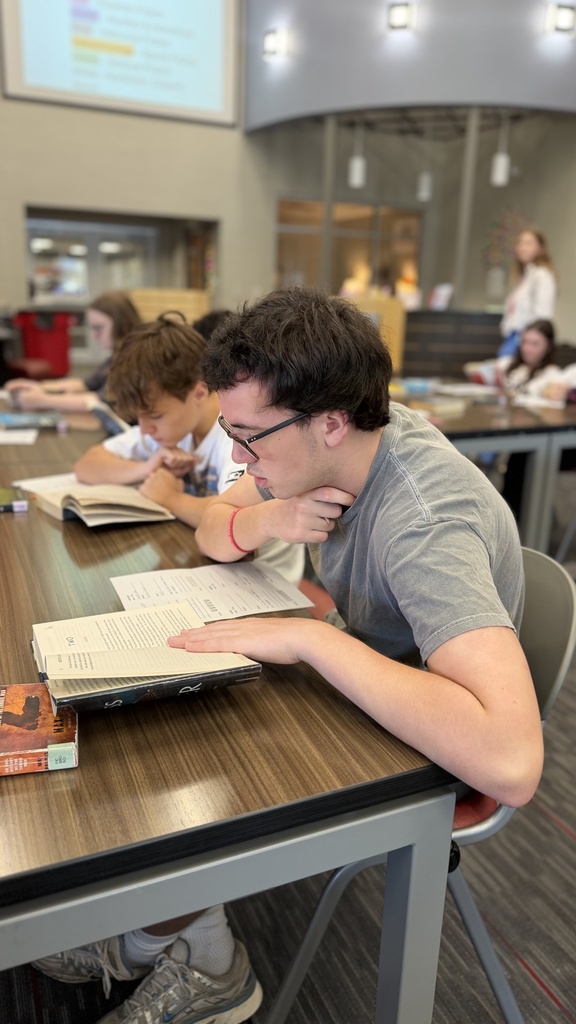 student reading a book at table in library