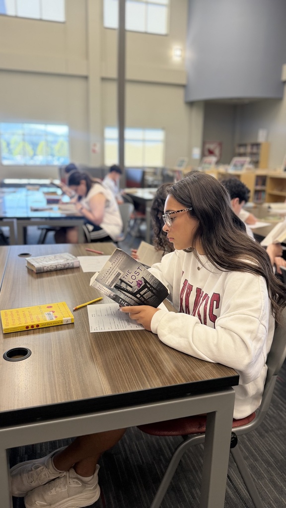 student reading a book at table in library