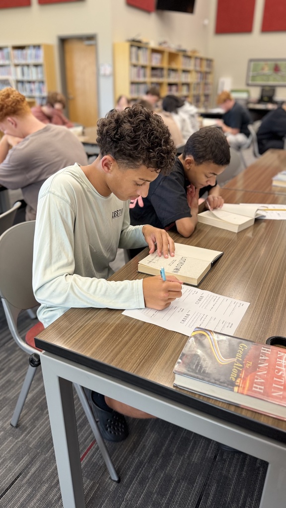 student reading a book at table in library