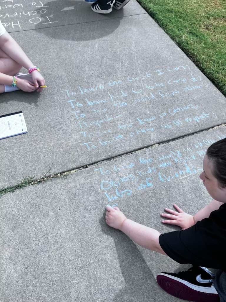 students writing a poem on the sidewalk in chalk