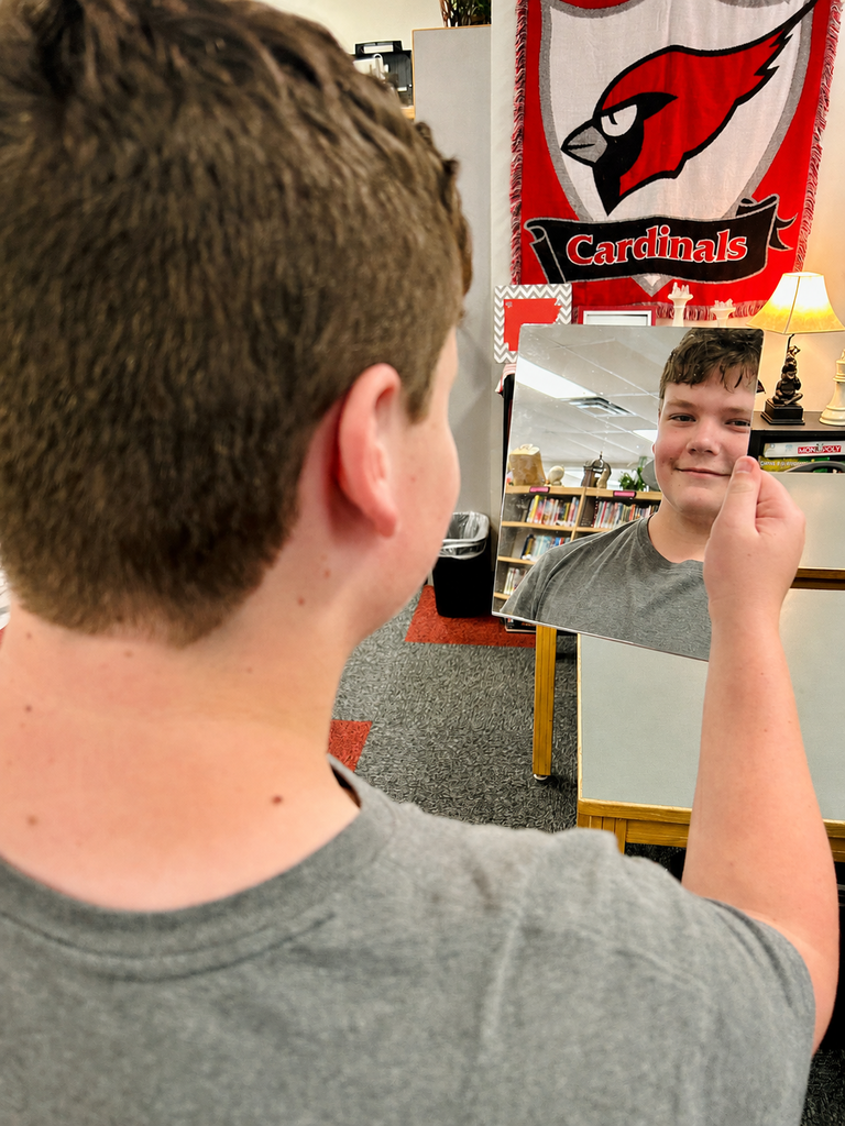 Student looks in mirror, smiles, during picture day