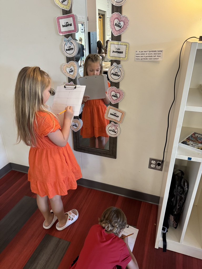 Two young children draw in a room with a mirror, a shelf, and a power outlet.