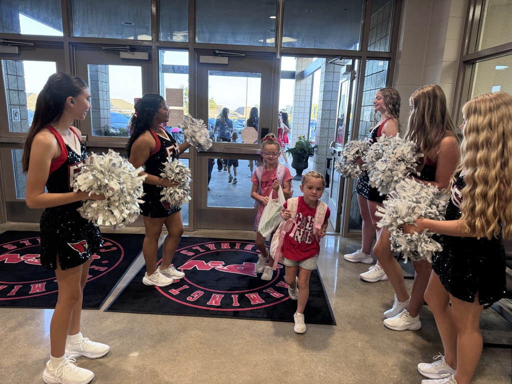 cheerleaders greeting students walking in to a building