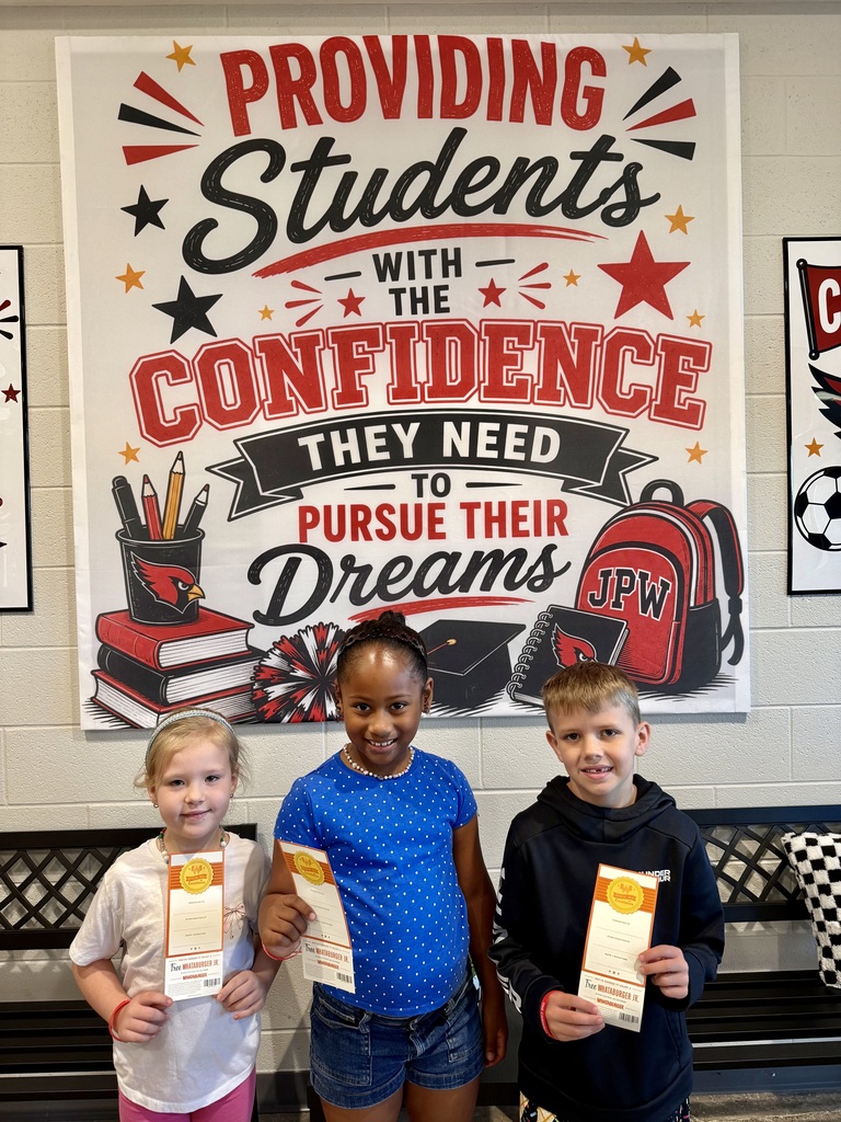 Three children holding certificates, standing in front of a motivational wall poster in a classroom.