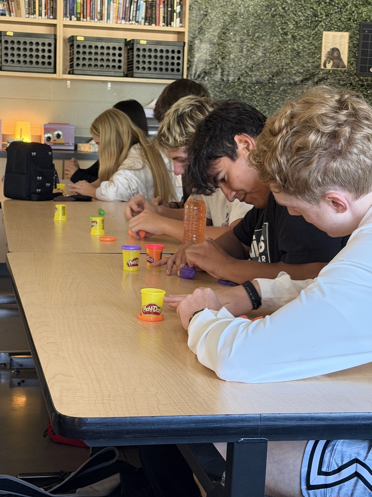 A group of people are seated around a table playing a game with small objects.
