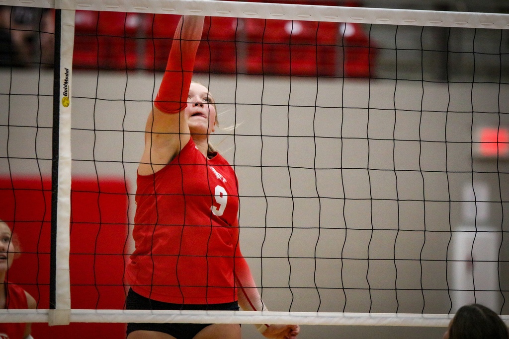 An indoor volleyball match with player in red and white uniform.