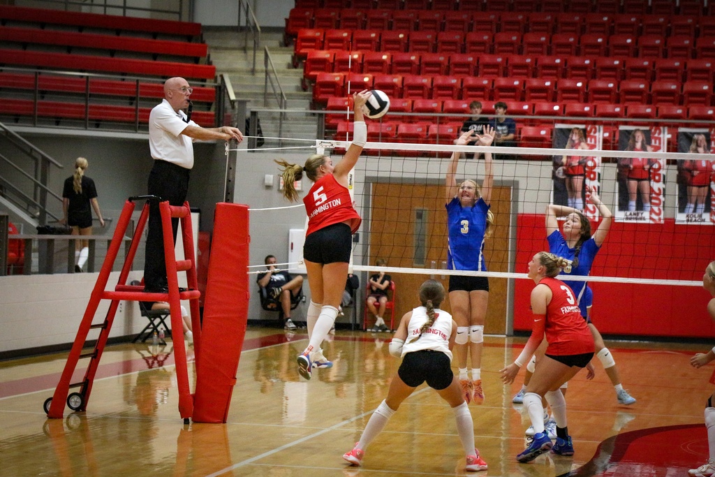 An indoor volleyball match with players in red and white uniforms.