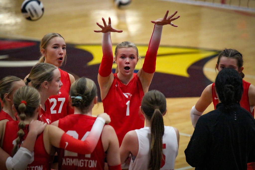 Players in red jerseys huddle on a court, with one player wearing number 1 and another 27.