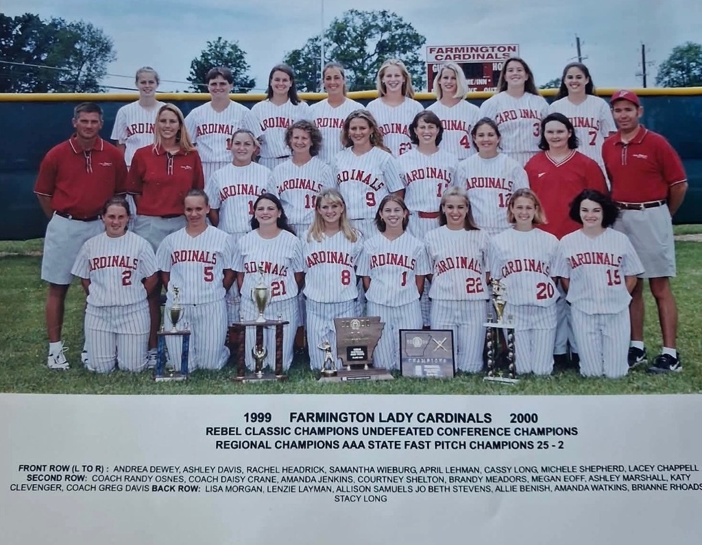 A sports team photo with players wearing red and white uniforms, holding trophies, and standing on a field.