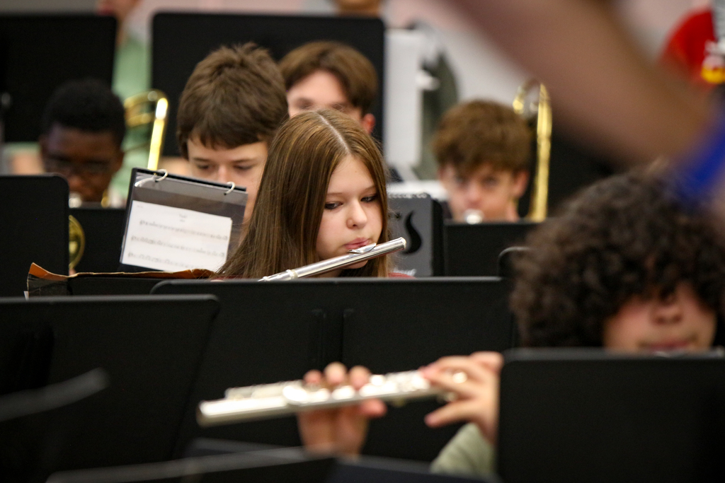 A school band with children playing various instruments, including a girl holding a flute.