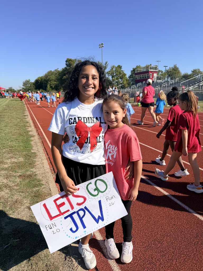 2 girls stand on track with sign