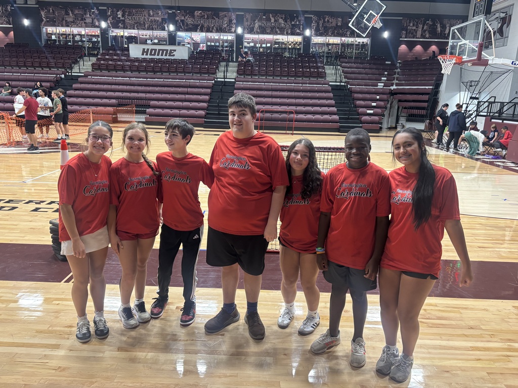 A group of people in red shirts pose for a photo on a basketball court.