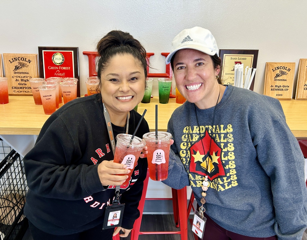 Two women hold drinks with straws. The woman on the left wears a black sweatshirt.